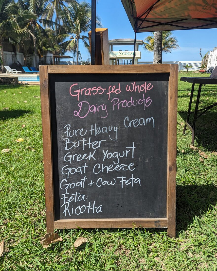 Chalkboard listing grass-fed whole dairy products at the Bitcoin Farmers Market, Club Cocal